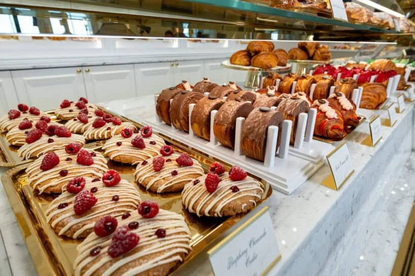 Croissants and raspberry pastries on gold trays in the display counter at Emma's Patisserie at The Equestrian Manor
