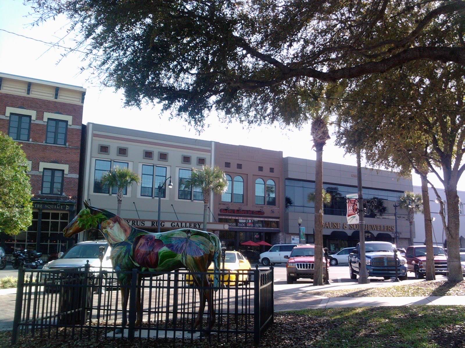Shops and historic storefronts facing the downtown square in Ocala, Florida, with a painted horse sculpture in the foreground