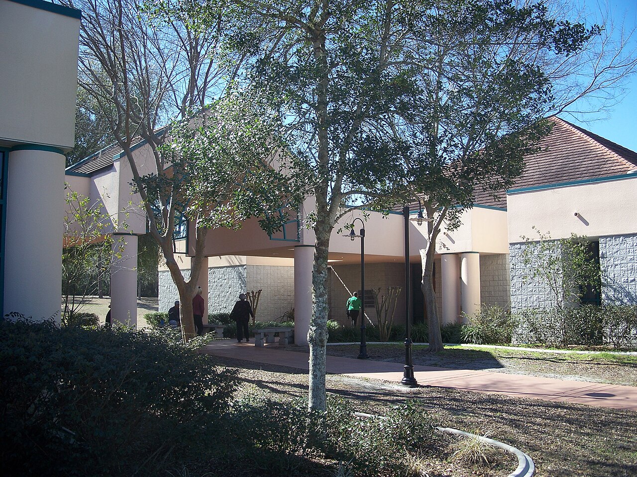 Covered walkway and entrance of the Marion Oaks Community Center, with visitors walking under shade trees