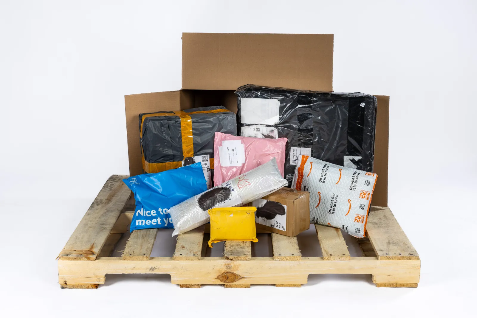 Unopened FUNDELIVERED mystery packages, including Amazon mailers and poly bags, stacked on a wooden pallet
