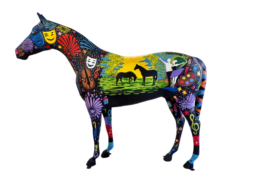 Brightly painted Celebration horse sculpture decorated with theater masks, a cello, ballet dancers, a paint palette and two horses grazing at sunrise