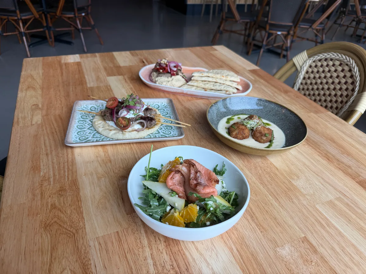 Mediterranean small plates including skewers on flatbread, falafel and a citrus salad on a wooden table at The Hammock inside The Forge Ocala
