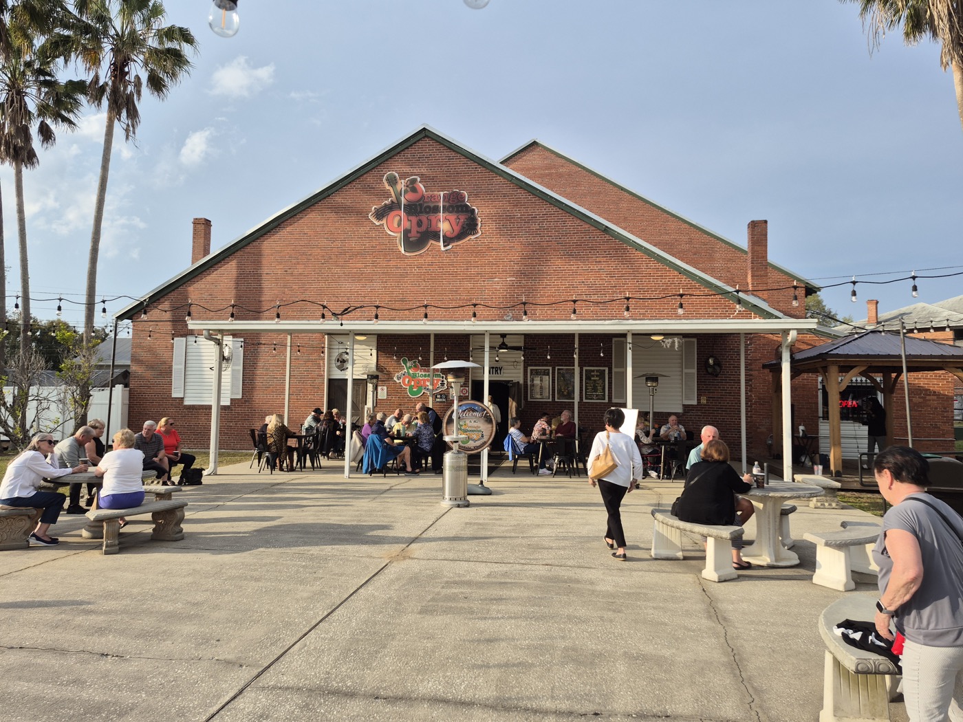 Red brick building with the Orange Blossom Opry sign, a covered porch and guests sitting at patio tables