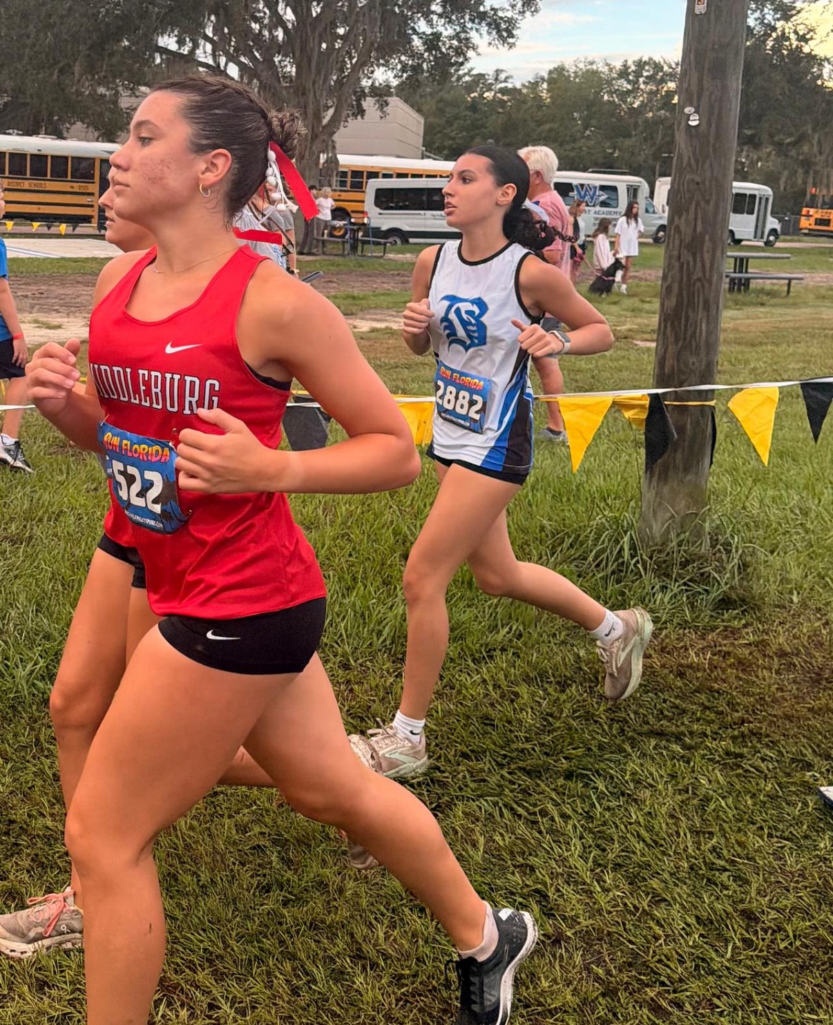 A Belleview runner racing behind a Middleburg runner in the varsity girls' 5K at the 2026 Buchholz Bobcats Classic
